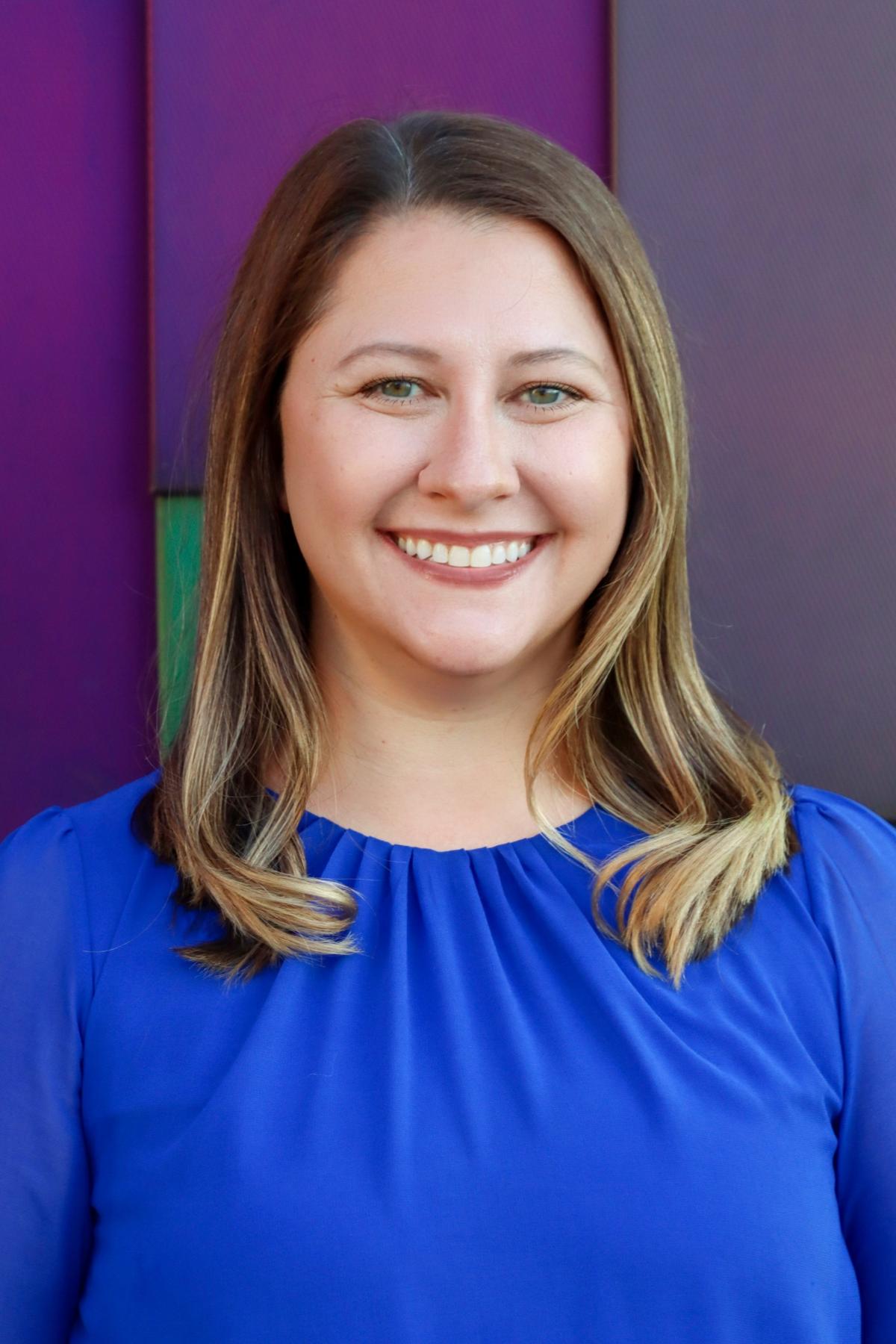 Lauren McCoy, with shoulder-length brown hair in a blue blouse.