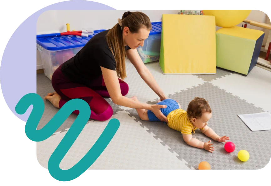 Therapist playing with a baby on a foam mat